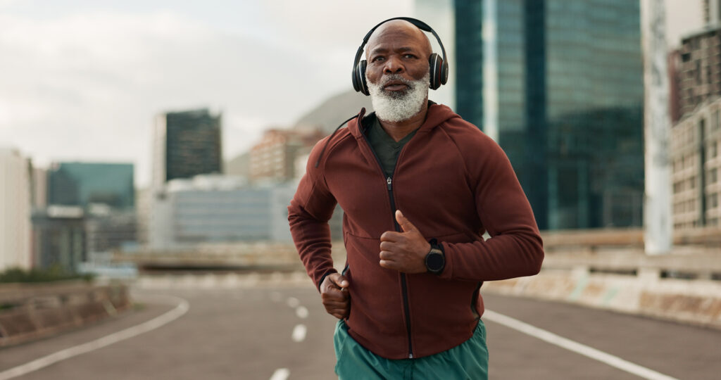 Mature, person and running in city with headphones for fitness, workout and marathon training music.