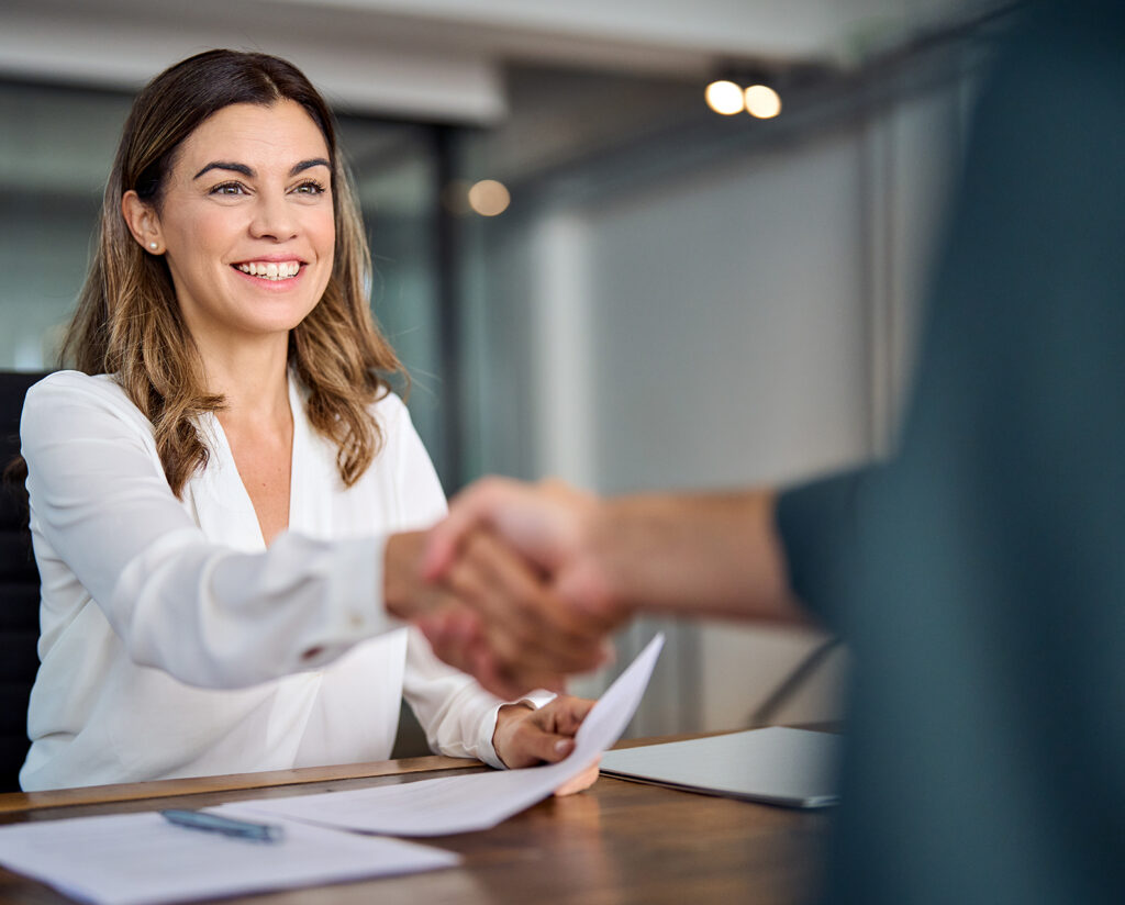 Happy mid aged business woman manager handshaking at office meeting. Smiling female hr hiring recruit at job interview, bank or insurance agent, lawyer making contract deal with client at work.