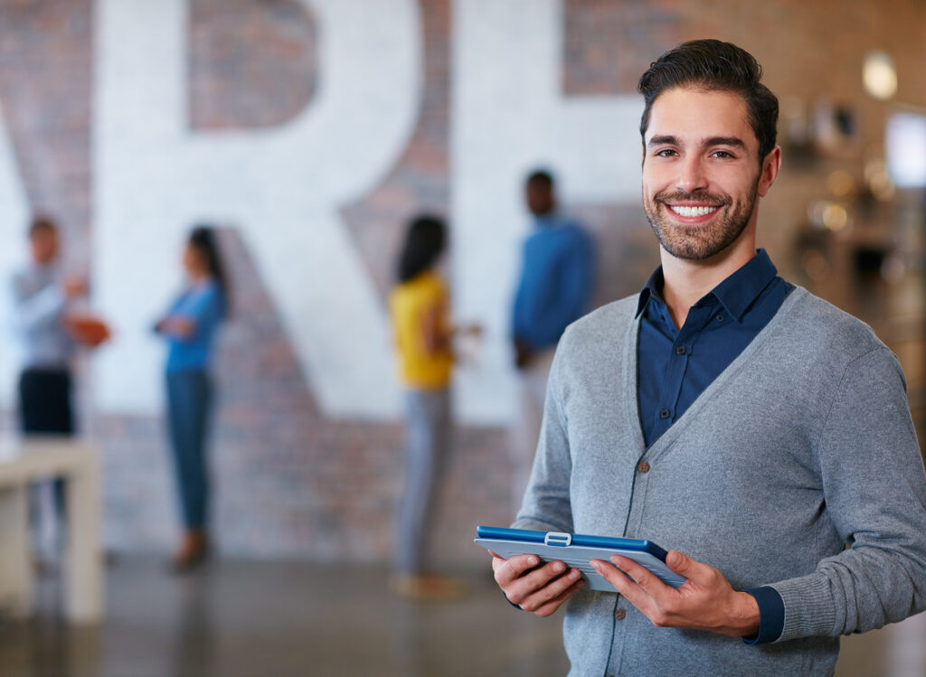 Cropped portrait of a young man standing with a tablet in the office